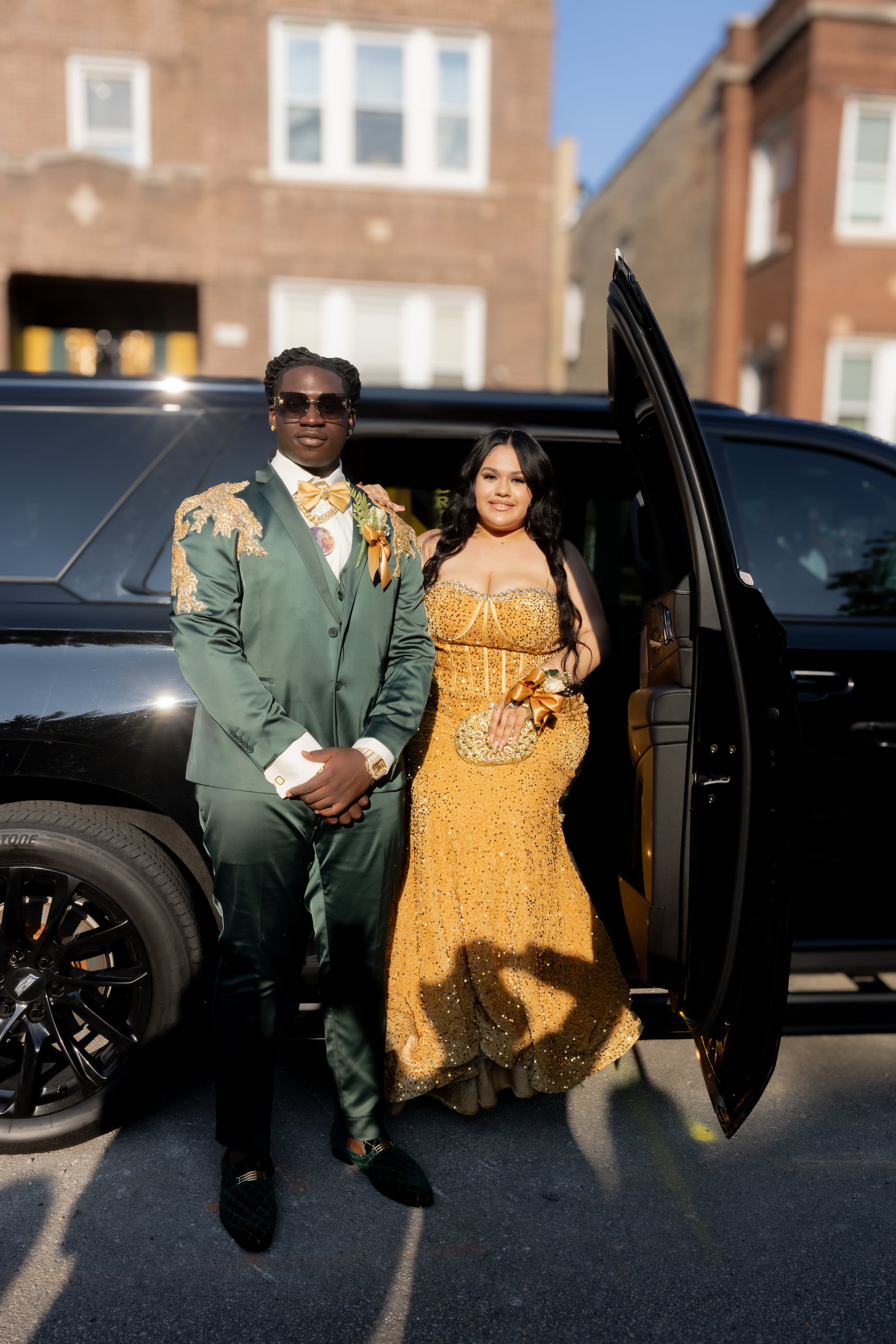 Prom couple in custom green and gold MBW Collections couture posing with Cadillac Escalade