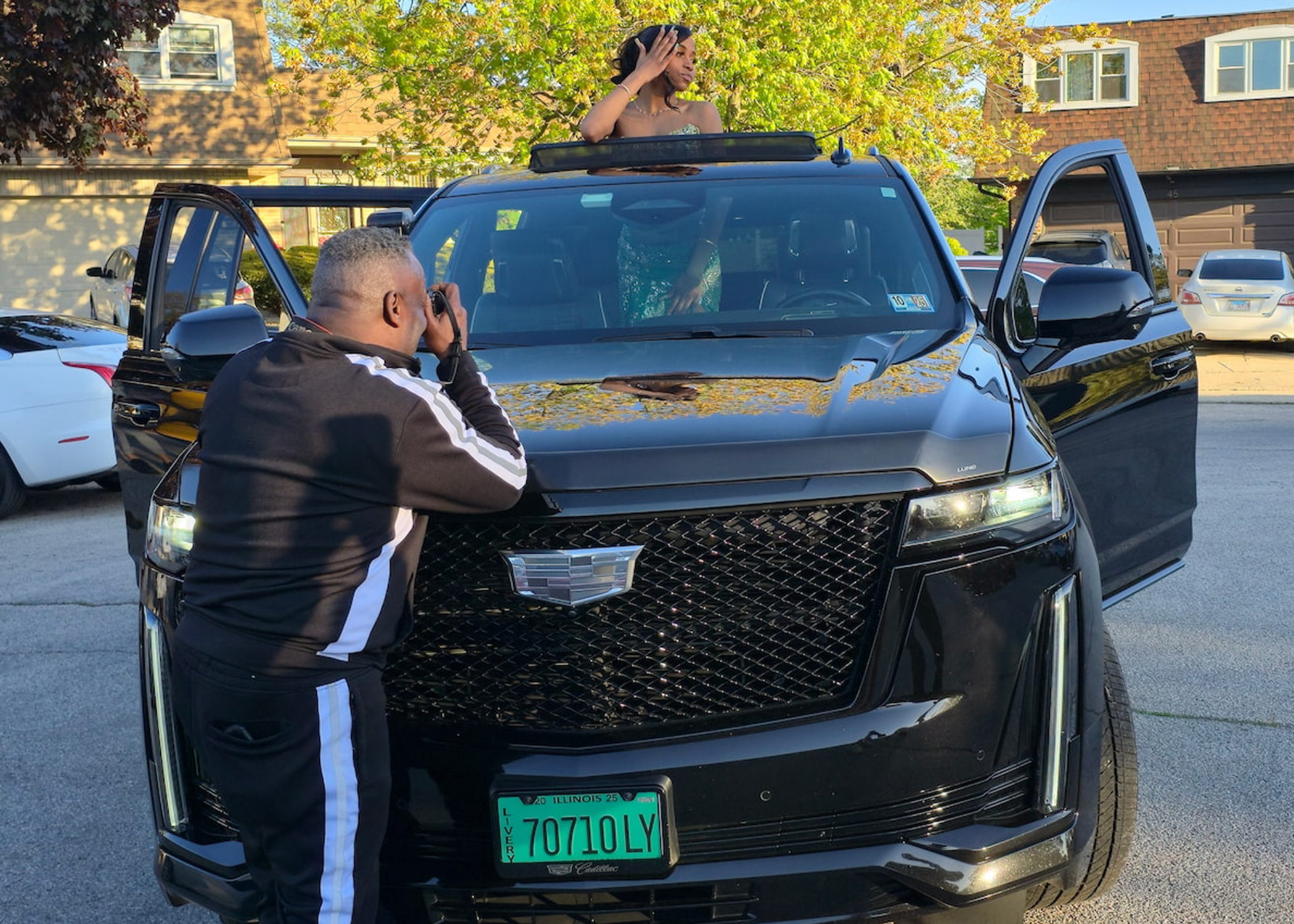 Prom send-off — young woman in custom emerald sequined MBW Collections gown through the moonroof of the Cadillac Escalade